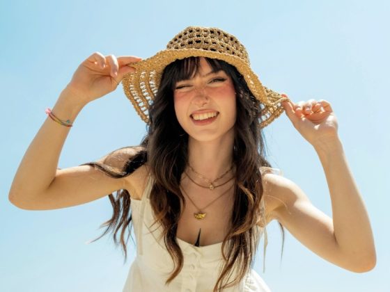 femme brune avec un chapeau qui sourit