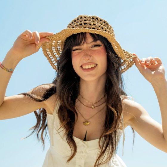 femme brune avec un chapeau qui sourit
